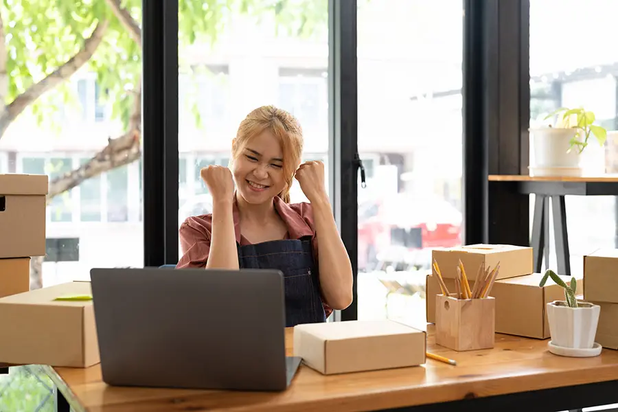 Excited business owner celebrating success while working on a laptop &mdash; representing entrepreneurs who&rsquo;ve turned their GoDaddy sites into professional, high-performing websites.