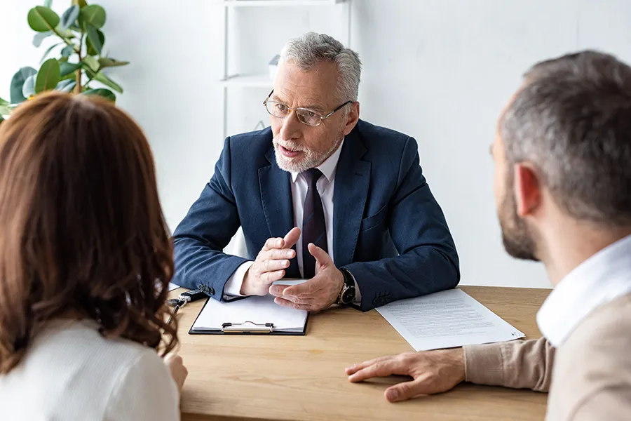 Experienced attorney discussing legal concerns with a couple during a consultation — representing law firm SEO strategies that help attorneys attract prospective clients, build trust, and grow their practices.