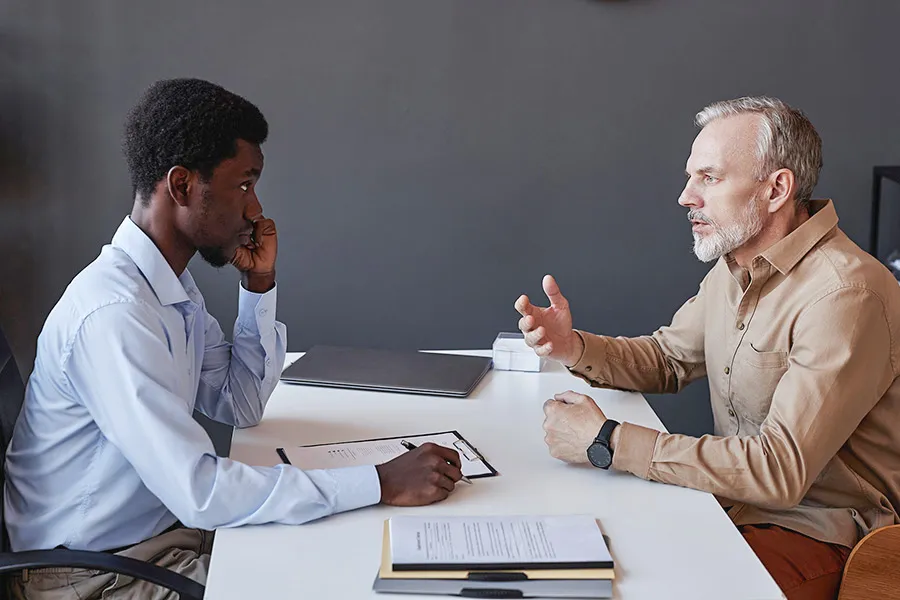 Legal professional listening and taking notes as a man explains his concerns — representing people searching for answers to legal problems before knowing which type of attorney or legal services they need.