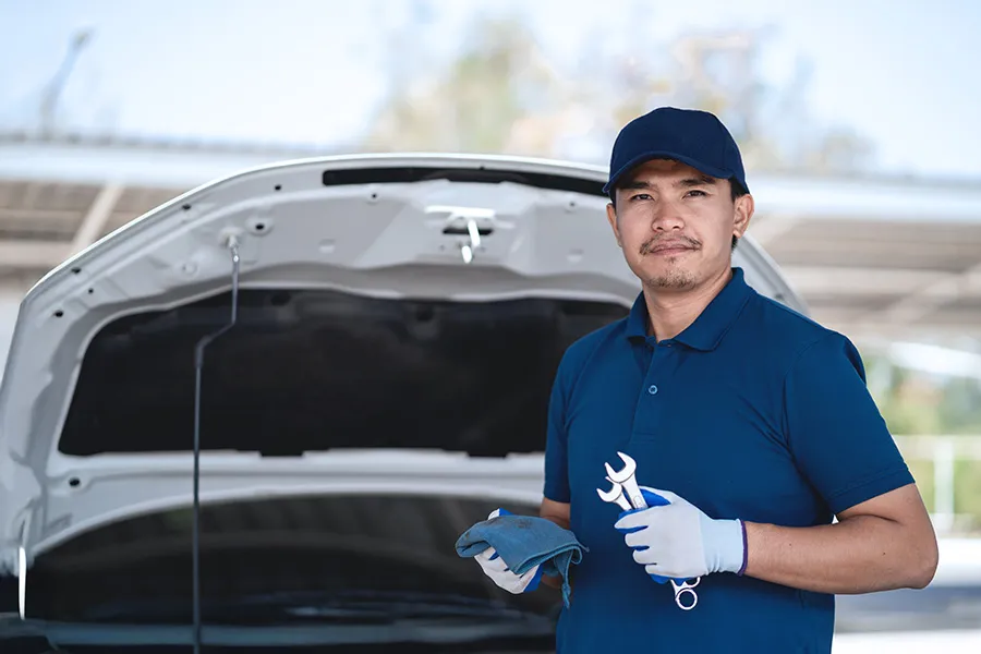 Mobile auto repair technician standing beside a vehicle with its hood open — representing local SEO for mobile mechanics and service area businesses that travel to customers throughout their surrounding communities.