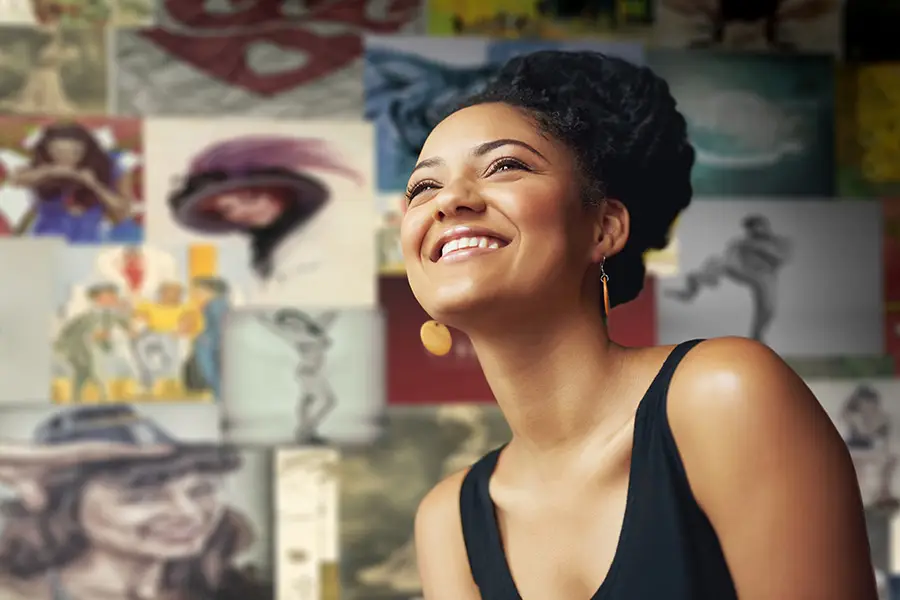 Smiling artist standing in front of her paintings — representing creative professionals with custom portfolio websites.