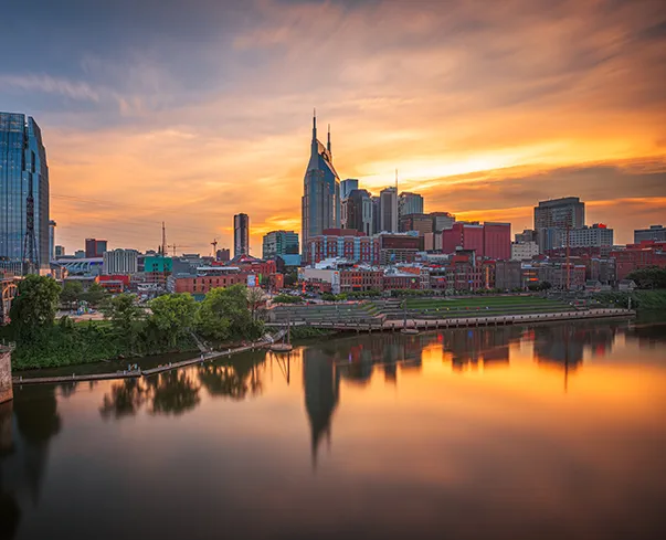 Nashville skyline at sunset viewed from the John Seigenthaler Pedestrian Bridge overlooking the Cumberland River in downtown Nashville TN.
