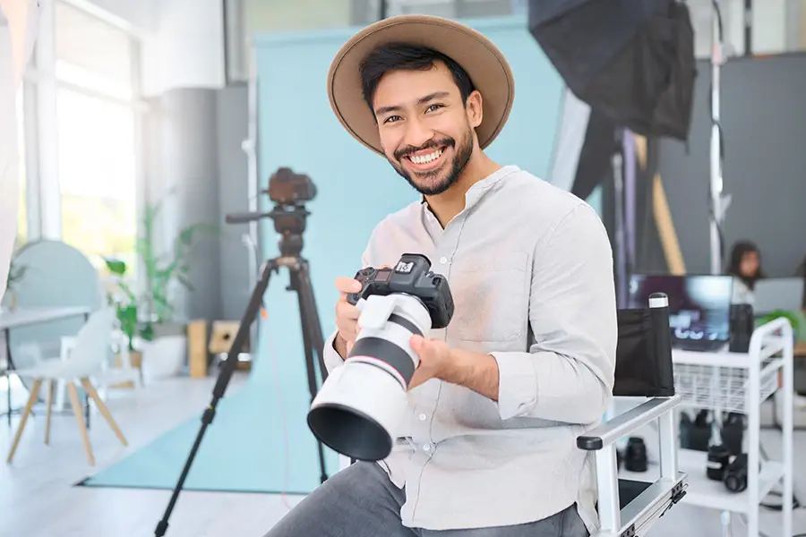 Photographer smiling in a studio with camera and lighting setup — representing professional website design for photographers and creatives.