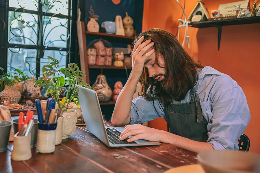 Small business owner frustrated while trying to build their own website — representing the challenges of DIY GoDaddy sites before hiring a professional.